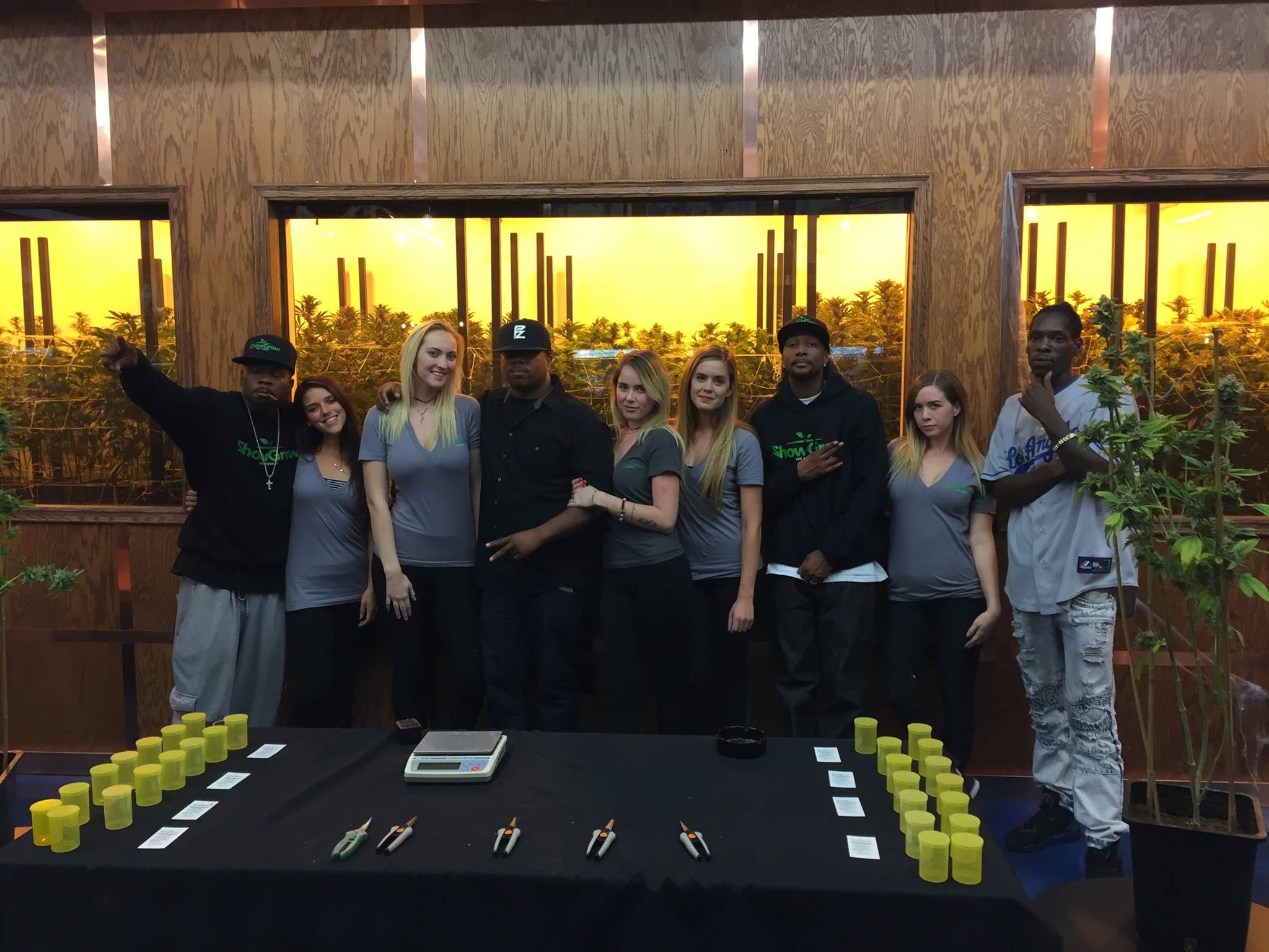 ShowGrow team standing in front of the visible grow room inside the dispensary
